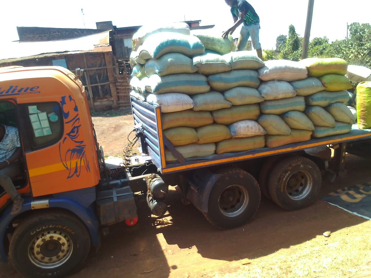 Sacks being loaded onto an orange truck at a collection point