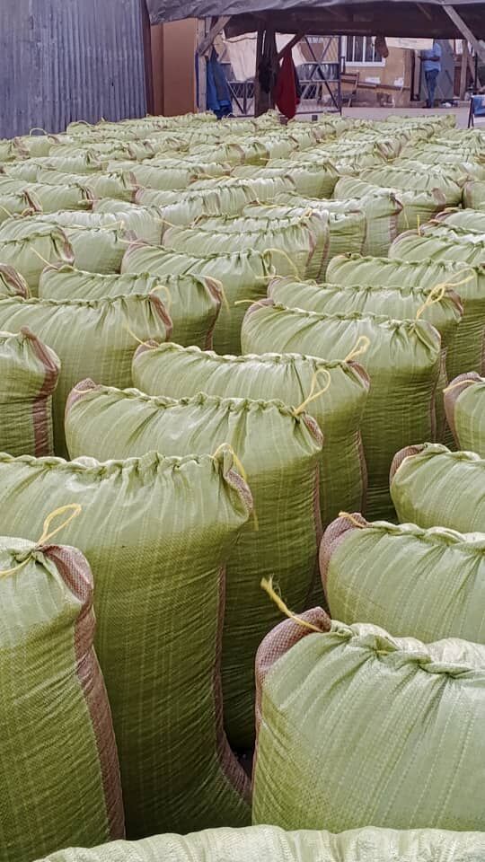 Rows of filled green woven sacks at an aggregation yard