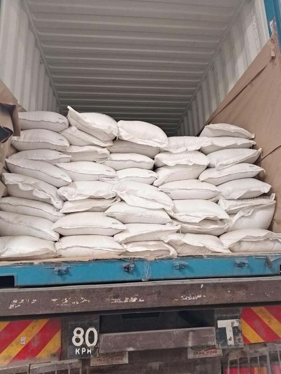 White sacks stacked inside a shipping container on a trailer